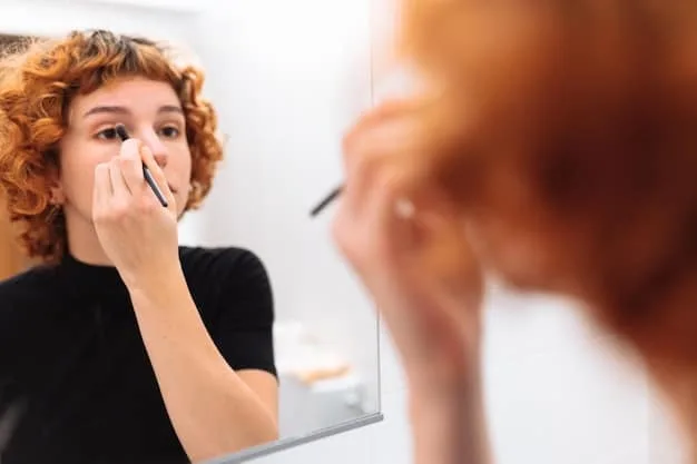 A close-up of a person gently using a cotton swab with precision to correct a small smudge of eyeliner on the outer corner of their eye, with other makeup tools blurred in the background.