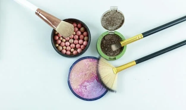 Overhead shot of a makeup artist's table with various setting powders, translucent and colored, along with powder brushes.