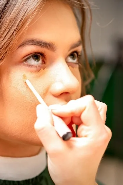 A close-up of a hand gently dabbing concealer under an eye with a beauty sponge, illustrating subtle application for a natural look.