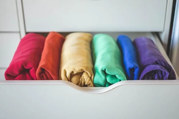 A close-up of a well-organized wardrobe with neatly folded clothes in a curated color palette of neutrals like white, black, gray, and beige, with a few vibrant accessories creating pops of color.