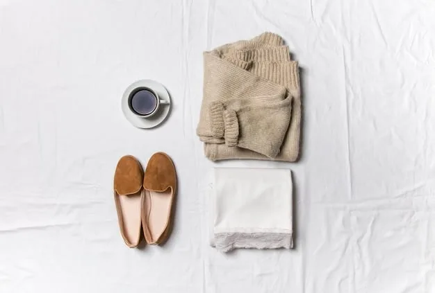 A flat lay of the seven essential capsule wardrobe pieces: a crisp white t-shirt, tailored black trousers, classic medium-wash jeans, a cozy neutral-colored cardigan, a versatile black knee-length dress, a sharp structured black blazer, and clean white sneakers, all neatly arranged.