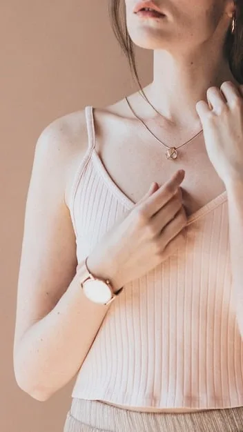 Close-up of hands accessorizing an outfit, showing a person adding a delicate necklace and a classic watch to a simple yet elegant blouse, focusing on the refined details.