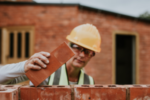 Homem fazendo a construção de uma casa com tijolo ecológico. 