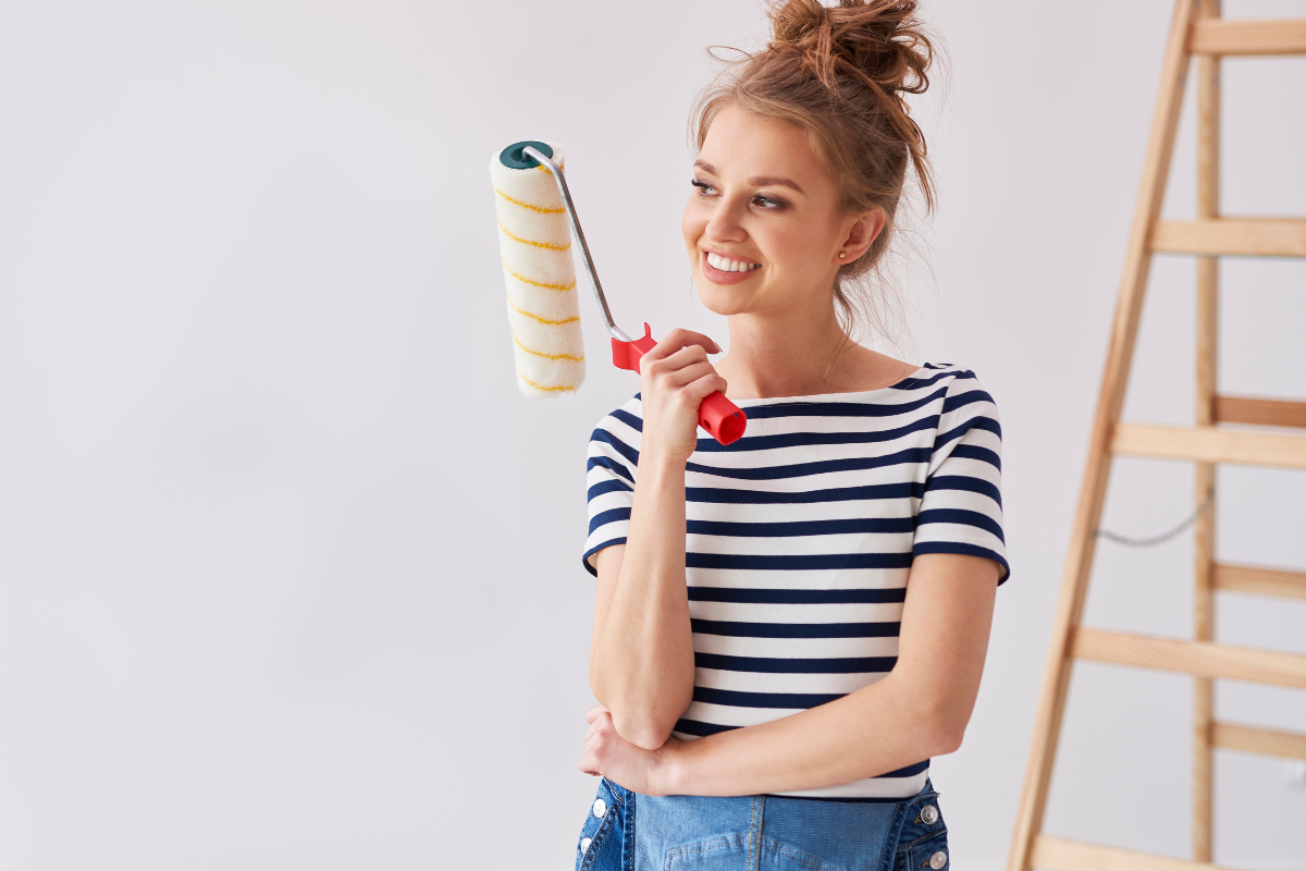 Mulher segurando equipamentos após descobrir como pintar a casa sem erros.