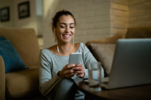 Mulher usando celular e computador ao descobrir melhorar wifi em casa.