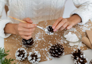 Pessoa fazendo a decoração de natal simples e barata com pinhas.