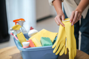 pessoa pegando luvas e produtos ao descobrir como organizar a rotina de limpeza.