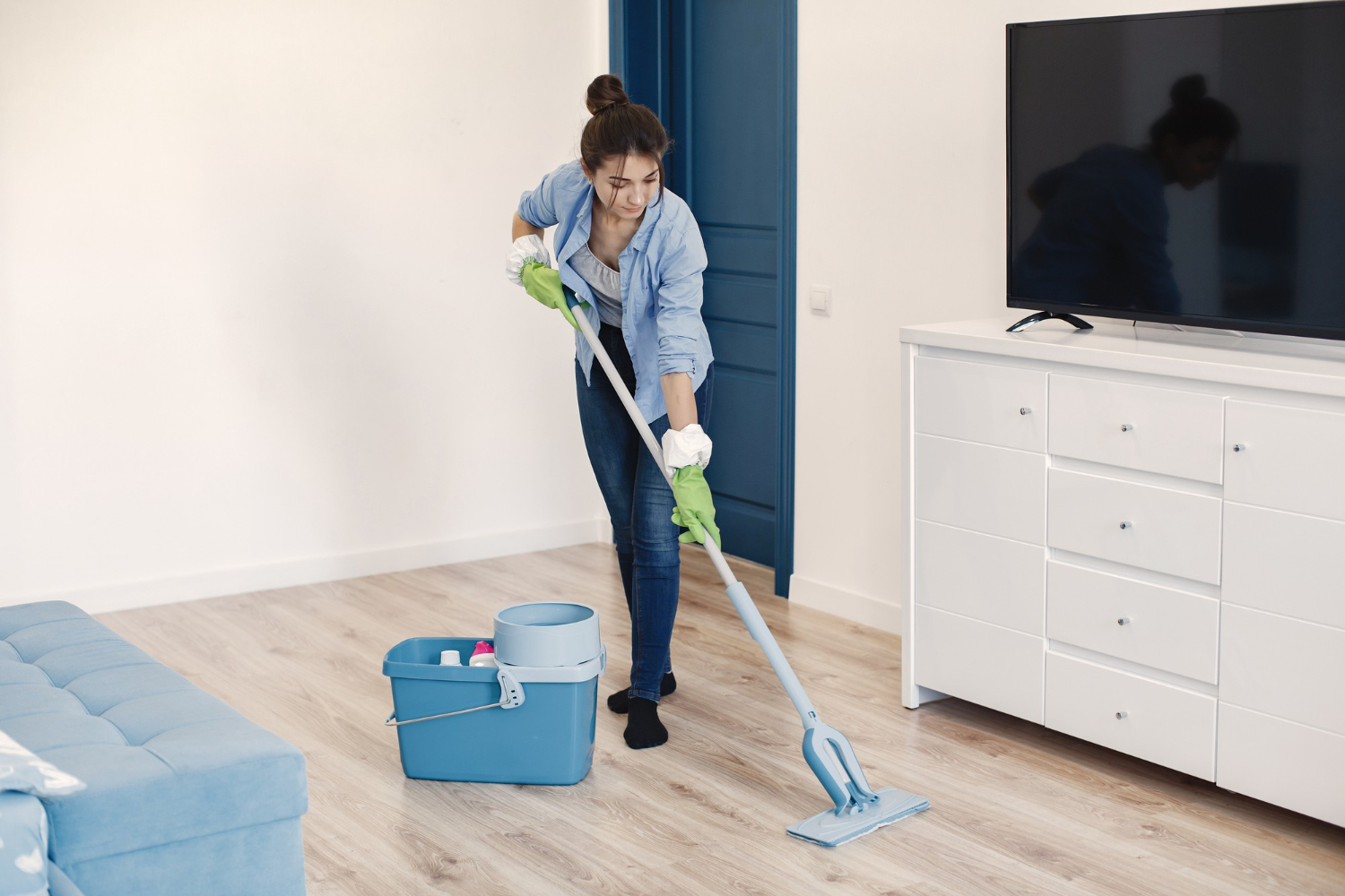 Mulher limpando o chão do apartamento ao saber como organizar a rotina de limpeza