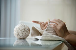 Pessoa fazendo uma peça em tricot para a decoração handmade.