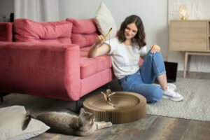 Mulher brincando com gato na sala de estar ao descobrir dicas de limpeza para quem tem pet. 