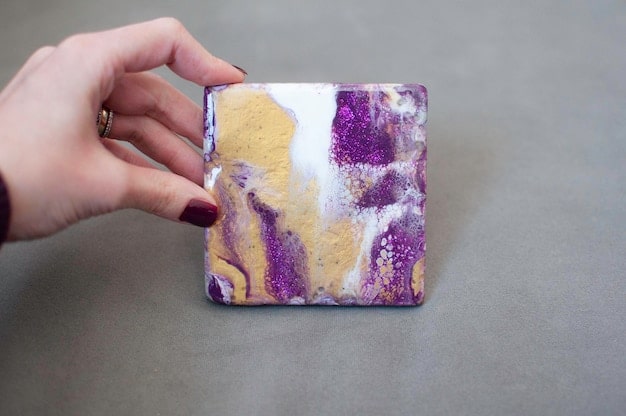 A hand gently wiping a custom resin art phone case with a soft microfiber cloth, showing the case's glossy, decorated surface.