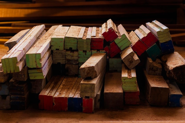 A stack of cleaned and cut reclaimed wood planks, neatly sized for a bookshelf project, resting on a workbench alongside a tape measure and a hand saw, indicating readiness for assembly.