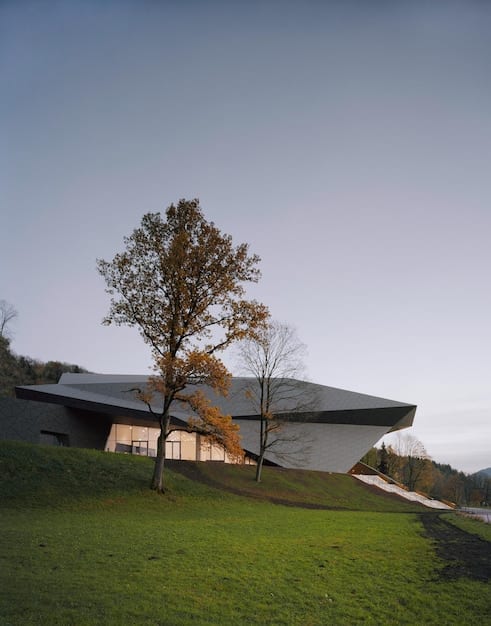 A strong, resilient house designed with wind-resistant features, surrounded by green landscaping and a clear sky, illustrating adaptable architecture.