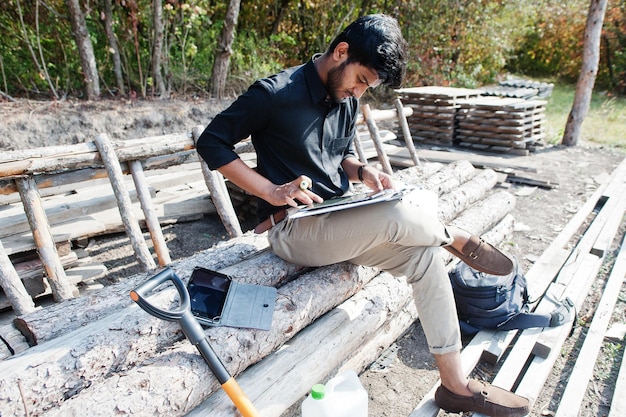 A construction worker is actively repairing a section of a damaged silt fence on a construction site, demonstrating immediate corrective action and diligent maintenance of erosion control measures.