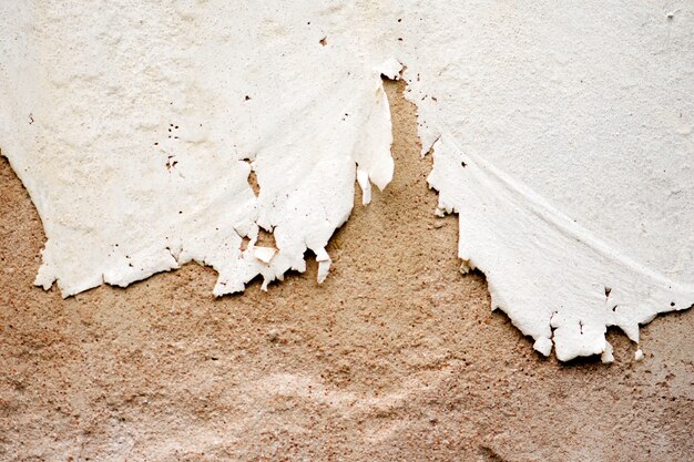 A close-up shot of a cracked and peeling wall due to poor paint quality or application, emphasizing the negative consequences of using low-quality materials or improper DIY techniques.