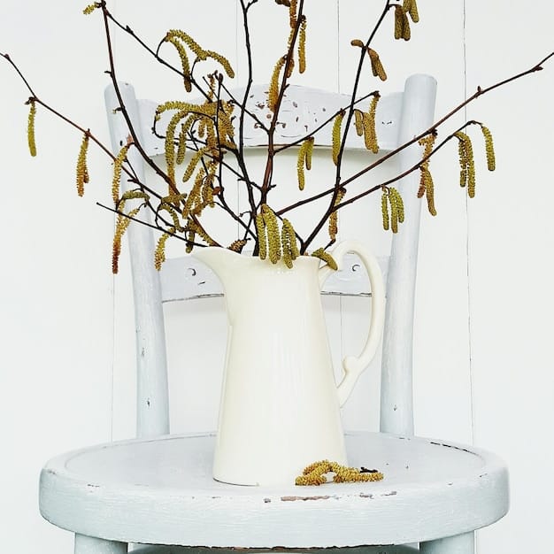 A close-up of a DIY painted old wooden side table with a modern vase and dried flowers, demonstrating a successful budget-friendly decor upgrade.
