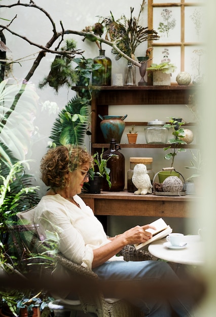A serene home office with a large window overlooking a lush garden, featuring several potted plants on the desk and shelves, a natural wood desk, and soft, earthy tones dominating the decor.