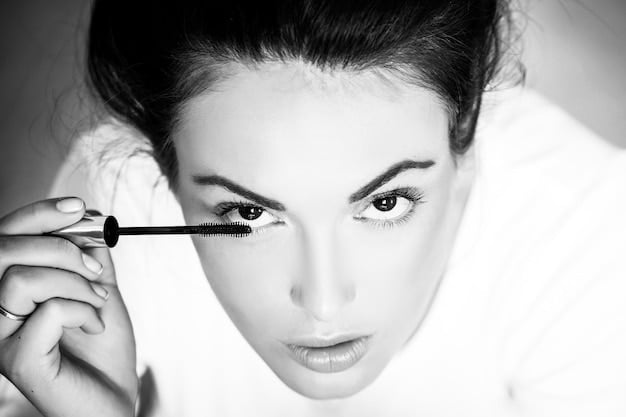 A perfectly applied sweep of black mascara on long, curled eyelashes, showing definition and separation against a soft, blurred skin background. The lashes are dramatically lifted and extended.