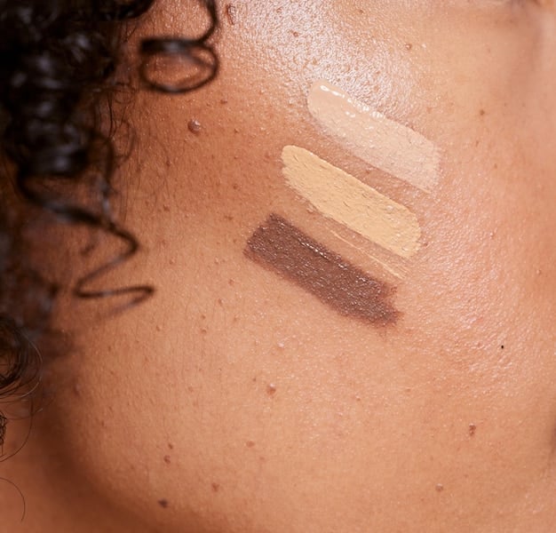 A close-up of a diverse model's cheek, showing a perfectly blended cream blush creating a natural, dewy glow appropriate for their medium skin tone, with soft focus on the surrounding skin.