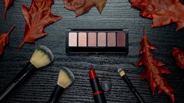A detailed flat lay of various makeup products including a dark eyeshadow palette, eyeliner, mascara, and a pair of luxurious false eyelashes, highlighting the finishing touches for a glamorous look.