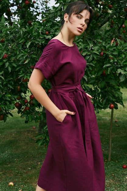 A woman with an apple body shape wearing an elegant empire-waist dress made of a flowing fabric, paired with delicate accessories, looking confident and stylish.
