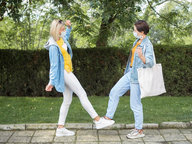 A person wearing stylish and comfortable overalls, paired with a white t-shirt and classic sneakers, casually walking with a large tote bag, indicating a day of errands. Bright, outdoor setting.