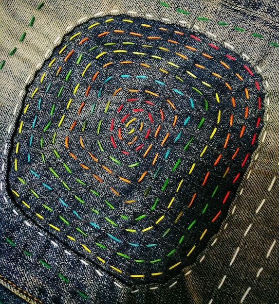 A close-up of a vibrant patchwork denim jacket, highlighting the intricate stitching and diverse fabric textures, showcasing the artisanal craft of upcycled fashion.