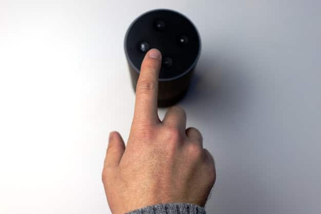 A person's hand pressing a mute button on a smart speaker, illustrating a direct action to enhance privacy.