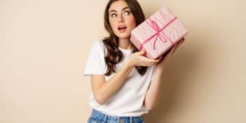 Celebration and holidays concept. Happy young girl looking intrigued, shaking box with gift, guessing whats inside wrapped present, standing over beige background